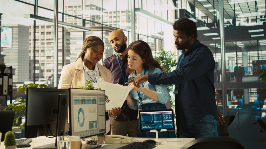 Portrait of smiling coworkers looking over revenue figures on paperwork
