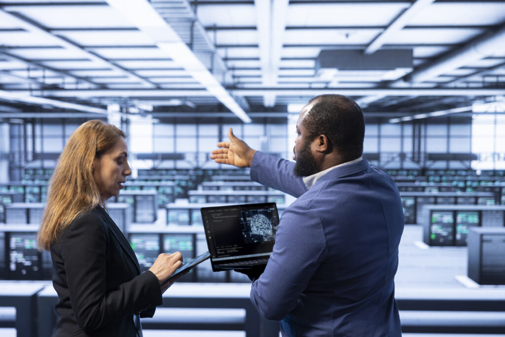 Team of technicians in data center using laptop to visualize AI